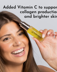 Smiling woman holding a small bottle of yellow Sweet Citrus face serum with a silver cap.