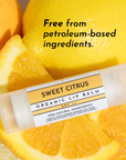 Lip balm tube labeled "Sweet Citrus Organic Lip Balm SPF 14" placed among halved oranges and lemons.
