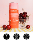 Red aluminum can of Cherry Punch Sparkling Electrolytes surrounded by fresh dark red cherries in a glass bowl on striped surf