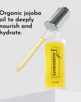 Clear glass dropper bottle with yellow serum and silver cap, featuring a dropper dispensing liquid.