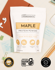 Just Ingredients maple protein powder pouch with 22g protein per serving, displayed with earbuds, notebook, and certification