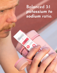 A person holds a pink shaker bottle with a Fruit Punch Electrolytes stick visible.