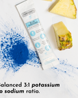 Blue powder scattered on a surface next to a stick packet and pineapple pieces.