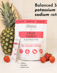 Fruit Punch Electrolytes package with a pineapple and strawberries on a marble surface.