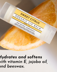 Lip balm tube resting on a slice of orange, featuring a label with product details and SPF information.