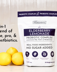 White pouch of Elderberry Lemonade Probiotic Complex next to three yellow lemons on light background.