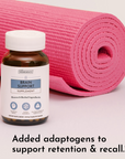 Brown glass bottle with white cap labeled "Brain Support Supplement" next to rolled pink yoga mat.
