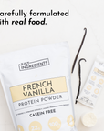 French vanilla protein powder bag with a single-serve packet and vanilla beans on a marble surface.