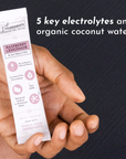A hand holds a stick packet labeled "Raspberry Lemonade Electrolytes" with nutritional information and benefits.
