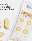 Peanut butter and chocolate protein powder stick next to whole peanuts on a marble surface.