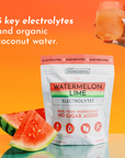 White pouch of Watermelon Lime Electrolytes with watermelon slice and glass of orange liquid on orange background.