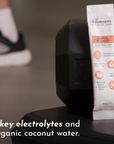 Electrolyte stick packet resting on a dumbbell, with text highlighting key features and ingredients.