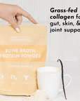 A hand holds a yellow pouch of bone broth protein powder next to a cup of liquid and a vanilla bean.