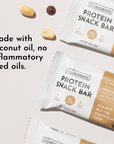 Two protein snack bars in packaging with peanut butter chocolate chip flavor, surrounded by nuts on a light background.