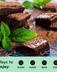Dark chocolate pieces are scattered with cocoa powder and fresh mint leaves on a wooden surface.
