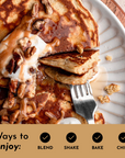 Pancakes topped with caramel sauce, nuts, and a dollop of cream, served on a light-colored plate.