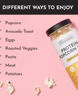 Container of cheddar cheese protein popcorn salt with popcorn kernels on a pink background, listing various uses.