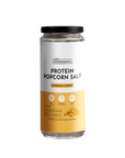 Clear jar of cheddar cheese-flavored protein popcorn salt with a white and yellow label, containing 5g of protein per serving