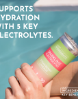 A hand holds a can of Strawberry Limeade Sparkling Electrolytes near a pool.