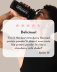 A person in a black tank top drinks from a shaker bottle with a label, featuring a quote about strawberry protein powder.
