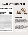 Coconut Chocolate protein stick next to chocolate pieces and a halved coconut.