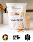Chai Protein Powder pouch with prepared shake in a glass on a kitchen countertop.