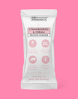 White stick pack packaging with pink accents reading “Strawberries & Cream Protein Powder” and nutrition callouts