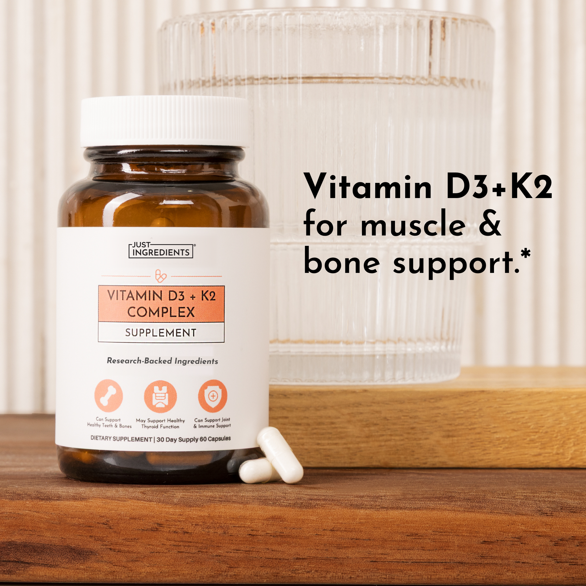 Amber glass bottle of Vitamin D3+K2 Complex supplement with white label next to clear glass container on wooden surface.