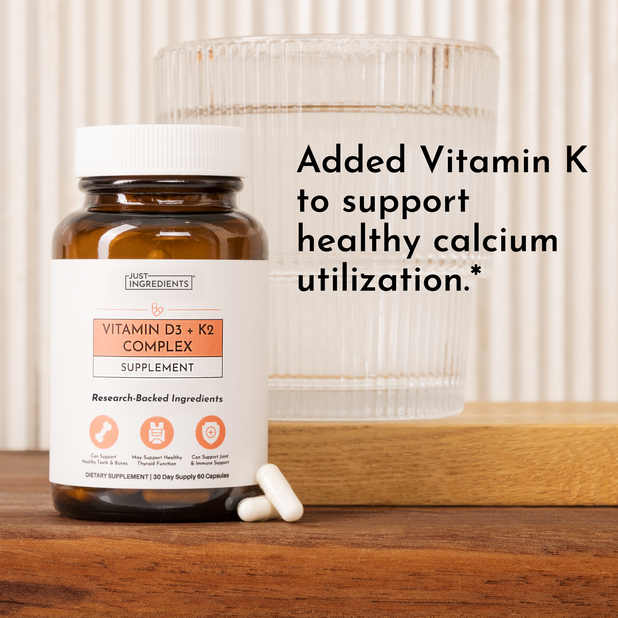 Amber glass bottle of Vitamin D3 + K2 Complex supplement with white label, containing capsules, displayed next to a glass of 