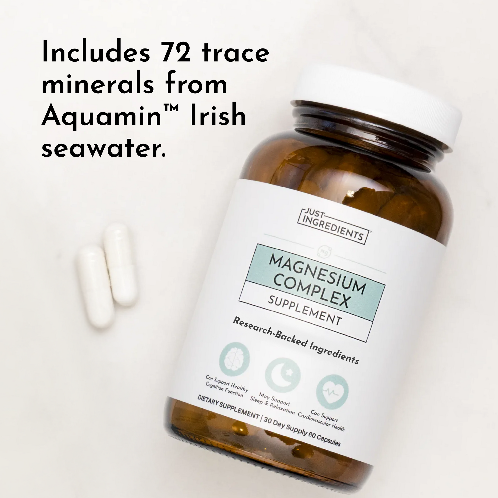 Magnesium Complex supplement bottle with white cap and two white capsules beside it on white background.