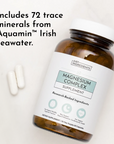 Magnesium Complex supplement bottle with white cap and two white capsules beside it on white background.