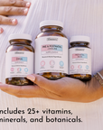Hand holding three brown glass supplement bottles labeled DHA, Pre & Postnatal + Choline, and Prenatal Iron against a white s
