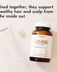 White scalp serum tube and amber supplement bottle labeled "Hair, Skin & Nails Complex" on marble background.
