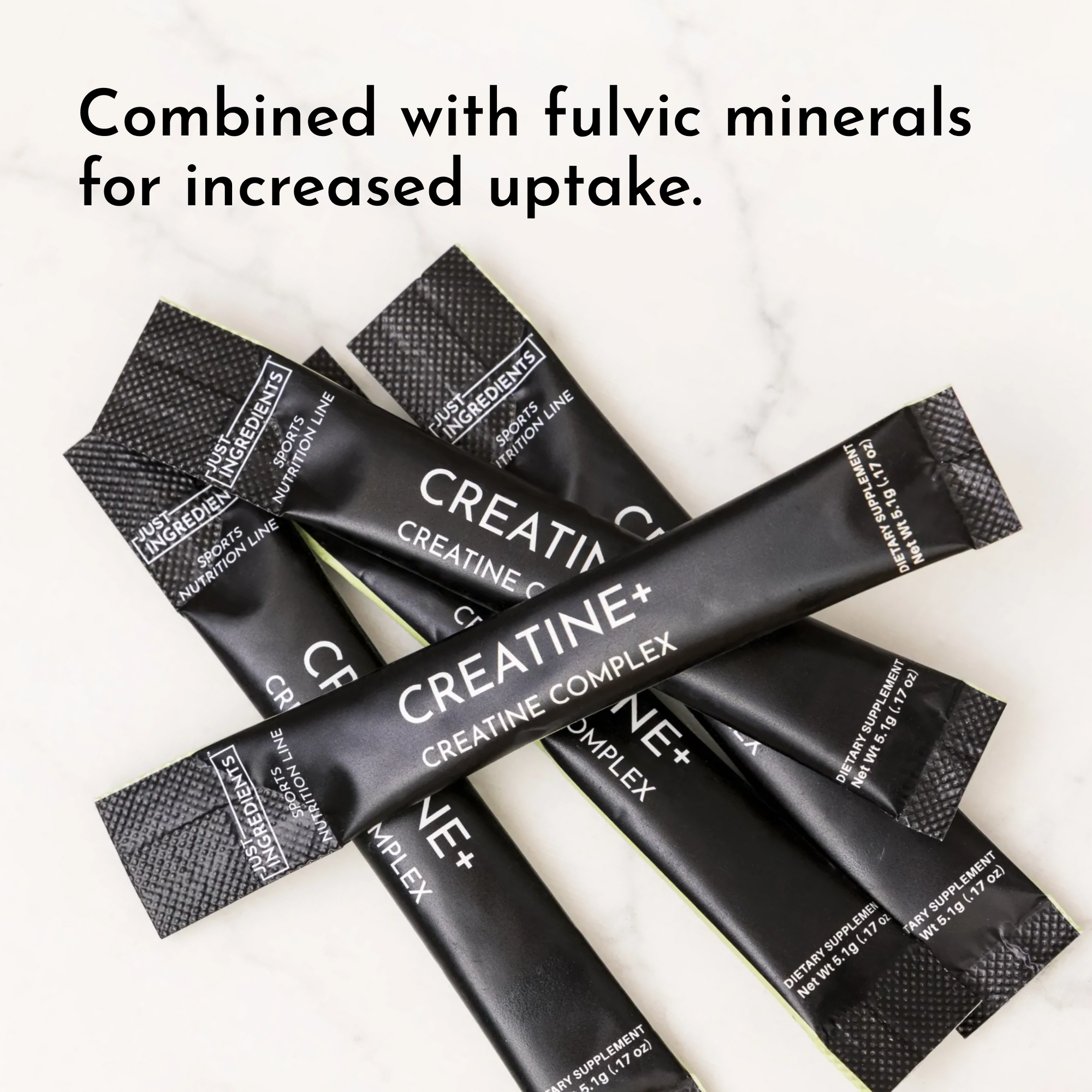 Multiple black Creatine+ stick packets with textured fold-top design arranged on marble surface.