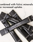 Multiple black Creatine+ stick packets with textured fold-top design arranged on marble surface.