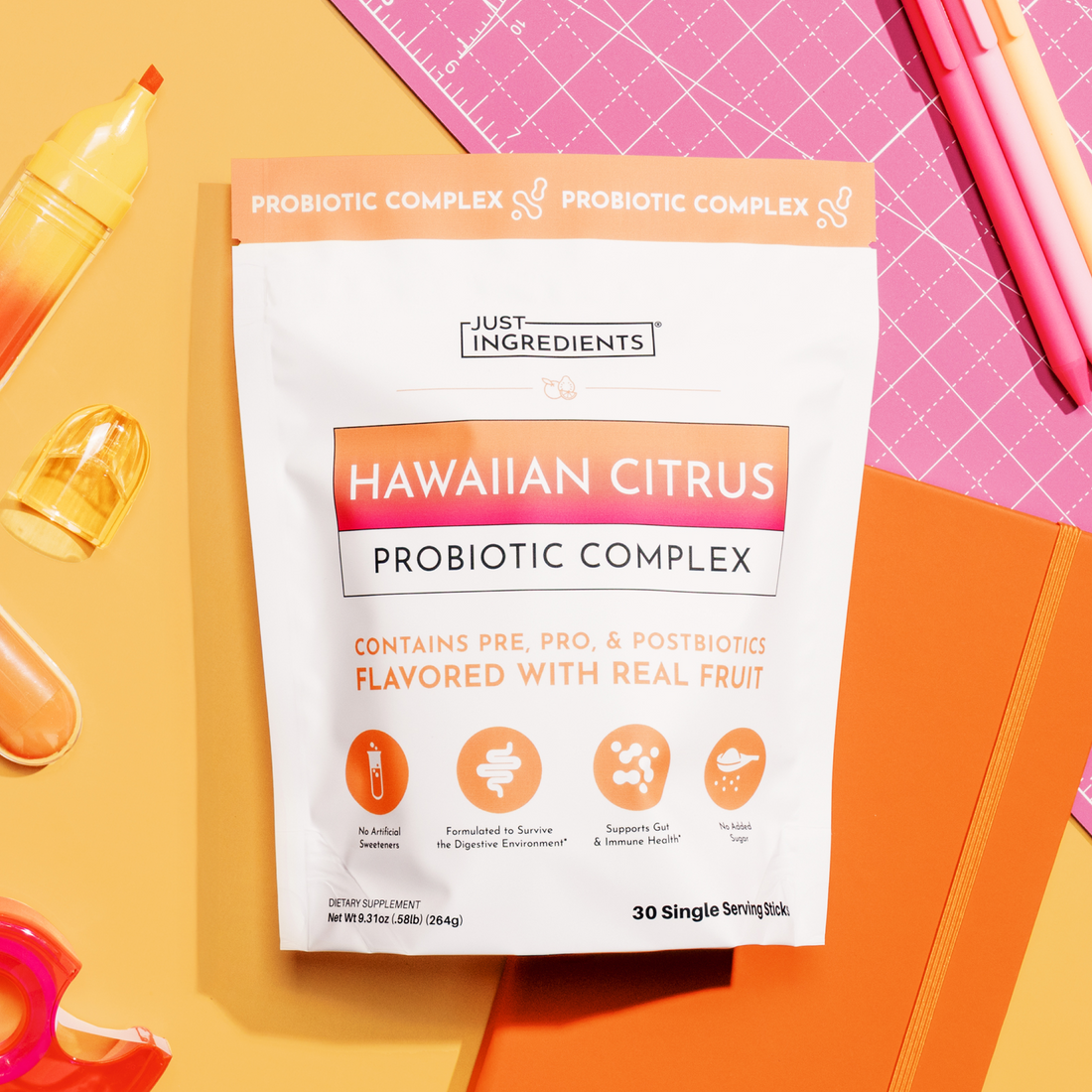 White packet labeled "Hawaiian Citrus Probiotic Complex" with orange gradient banner, surrounded by citrus beverages and pink