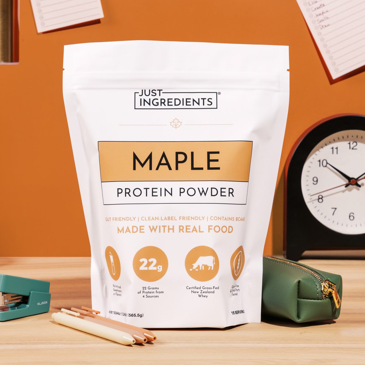 White pouch of Just Ingredients Maple Protein Powder with 22g protein per serving, displayed on orange background with clock 