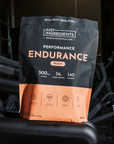 Black and peach pouch of Just Ingredients Performance Endurance drink mix with nutrition information displayed, sitting on ex