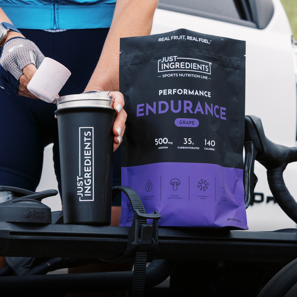 Person holding black tumbler and purple grape endurance drink powder packet with nutrition information displayed.