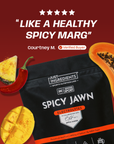 Black pouch of Spicy Jawn Electrolytes with red chili pepper, pineapple, and papaya arranged on burgundy background.