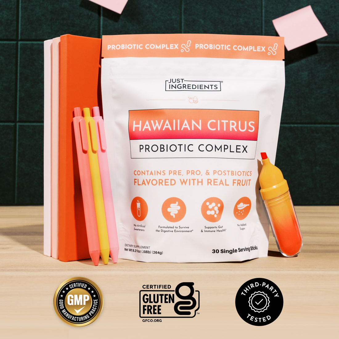 White pouch of Hawaiian Citrus Probiotic Complex with orange accents, surrounded by orange notebooks, colored pens, and a jui