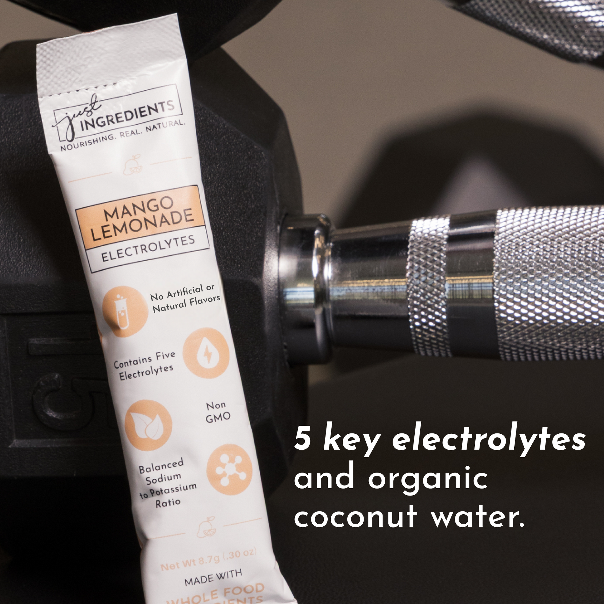 Electrolyte stick in mango lemonade flavor placed next to a dumbbell on a gym surface.