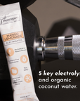 Electrolyte stick in mango lemonade flavor placed next to a dumbbell on a gym surface.