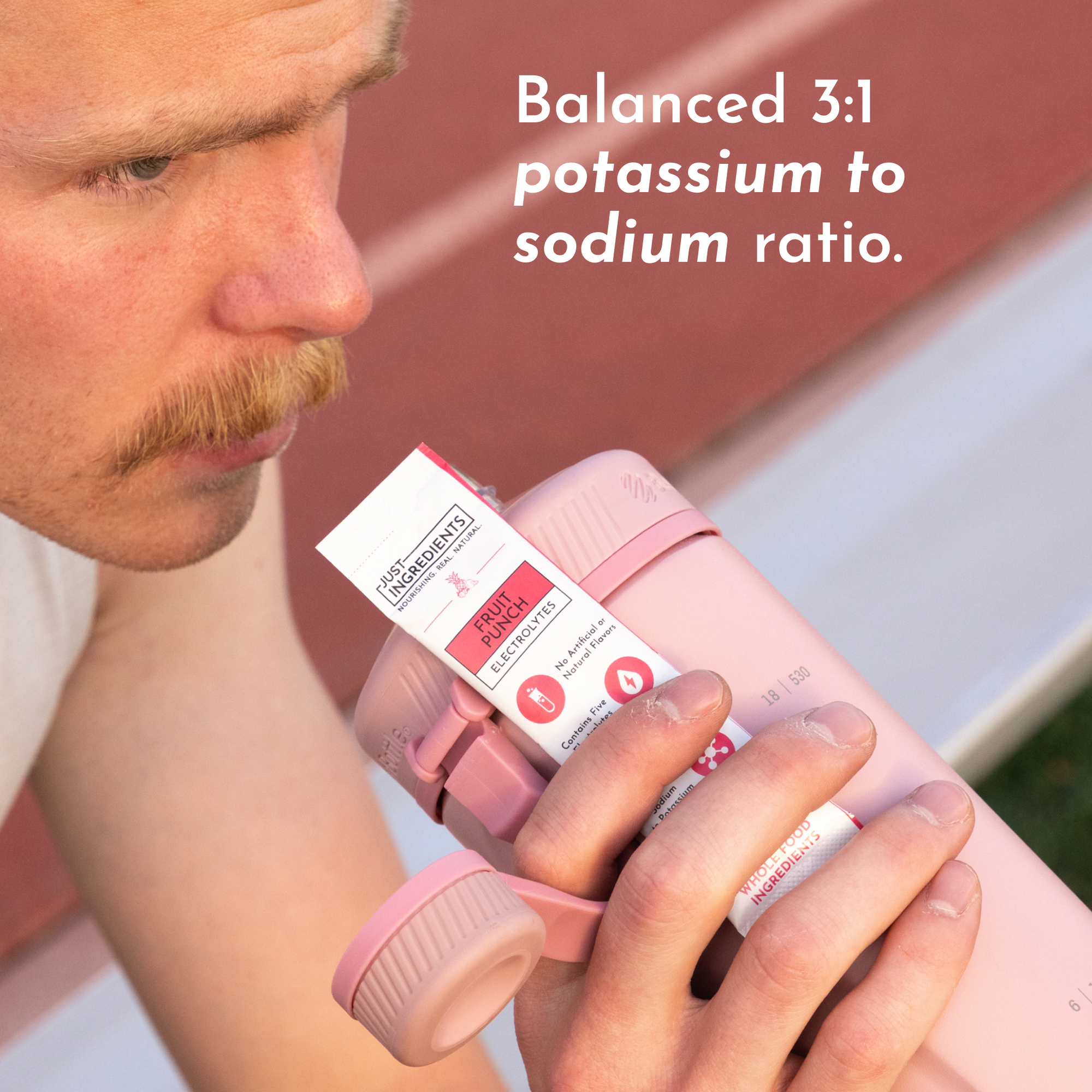 A person holds a pink shaker bottle with a Fruit Punch Electrolytes stick visible.