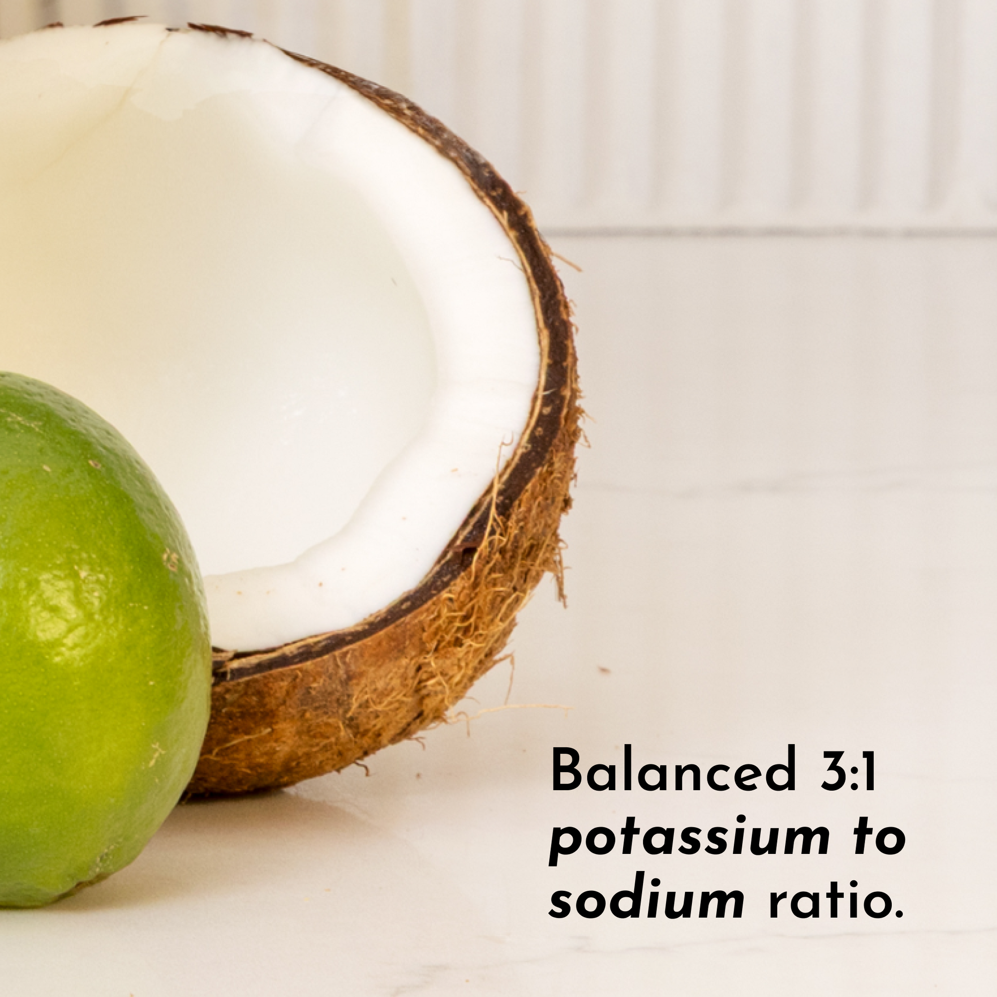 A halved coconut shell sits next to a whole lime on a light surface, with text about a potassium to sodium ratio.