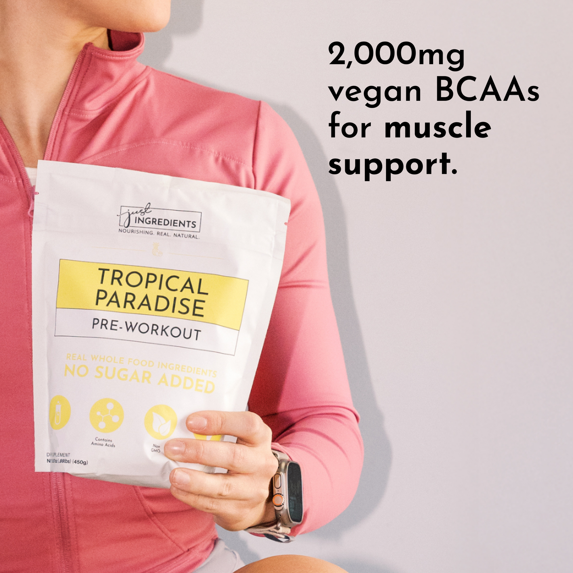 A person in a pink jacket holds a bag of "Tropical Paradise Pre-Workout" with nutritional information visible.