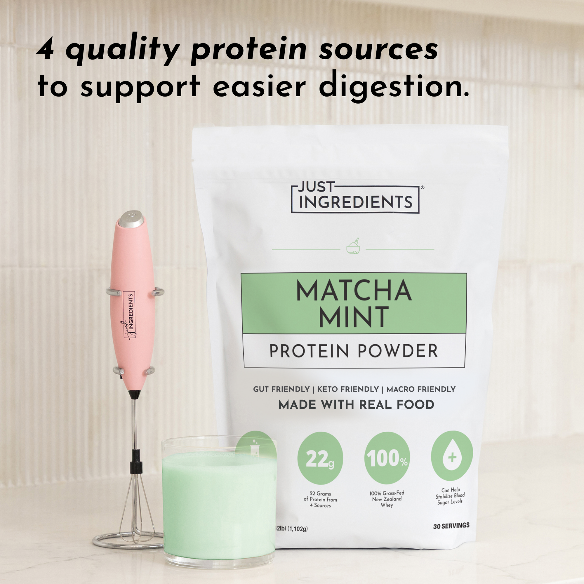White pouch of matcha mint protein powder beside a pink milk frother and green matcha latte in a glass.