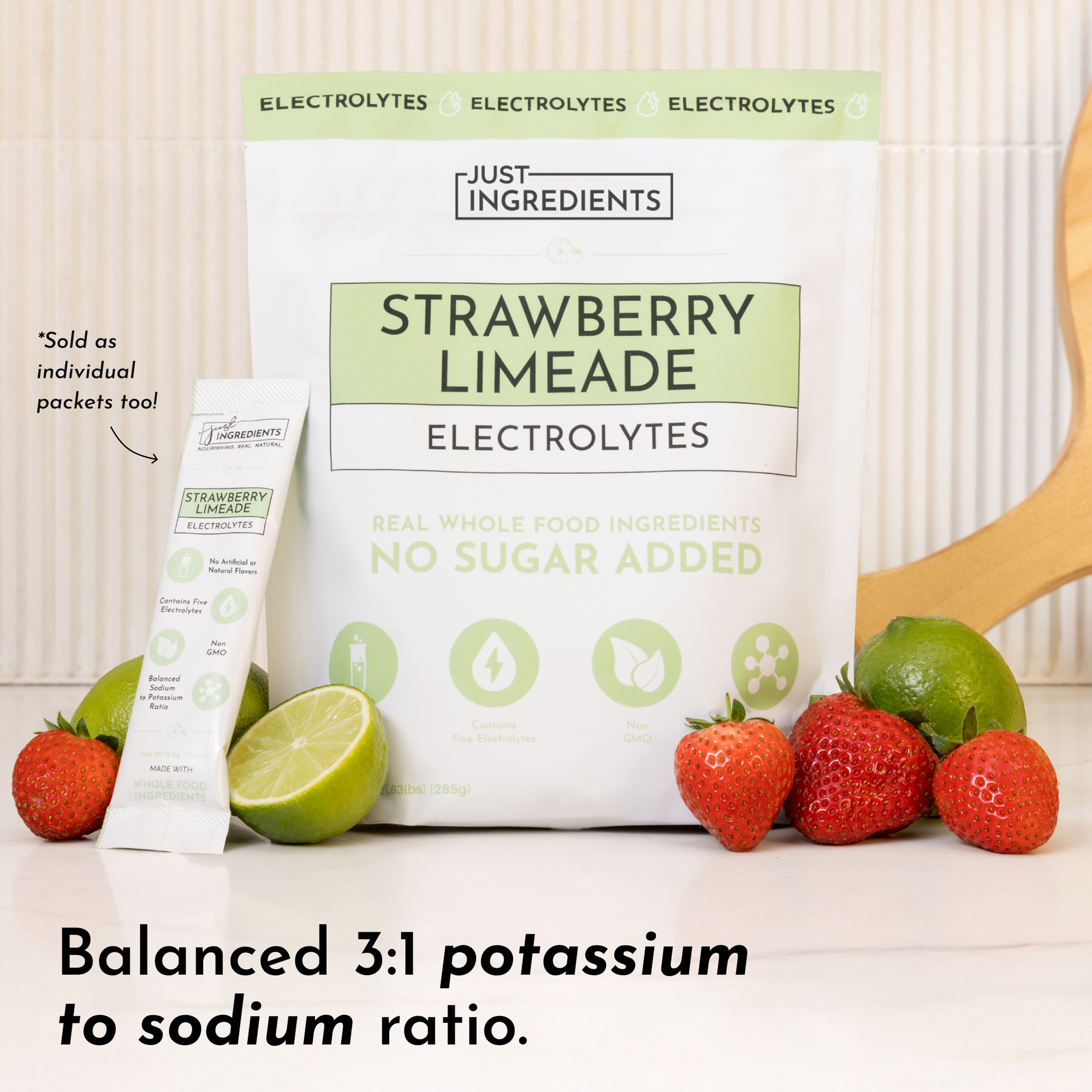 Pouch of Strawberry Limeade electrolytes with a single packet, fresh strawberries, and lime halves on a countertop.
