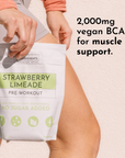 A person holds a pouch labeled "Strawberry Limeade Pre-Workout" with visible text about its ingredients and benefits.