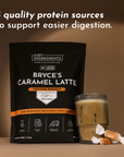 Black pouch of Bryce's Caramel Latte protein powder next to a glass of caramel-colored beverage and wrapped caramels.